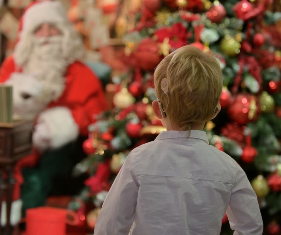 Un enfant devant le sapin de Noël et le Père Noël